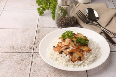 Photo of Delicious rice with parsley and mushrooms served on tiled table, space for text