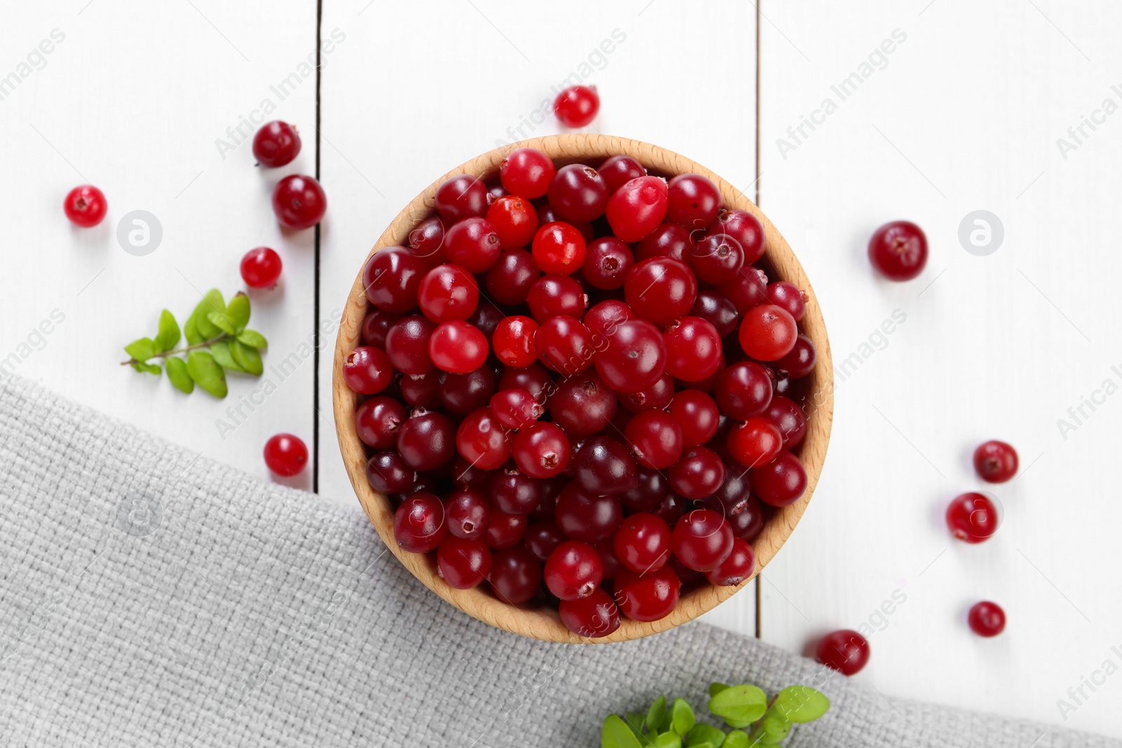 Photo of Fresh ripe cranberries and branches on white wooden table, top view