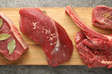 Pieces of raw beef meat and spices on grey textured table, top view