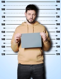 Image of Criminal mugshot. Arrested man with blank card against height chart