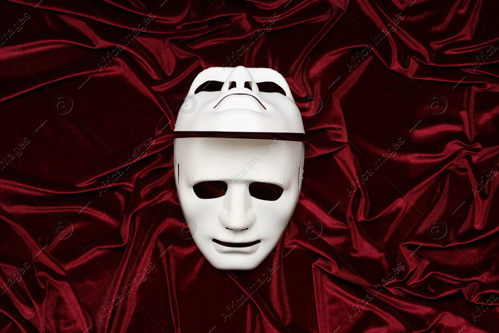 Photo of Theater arts. White masks on red fabric, top view