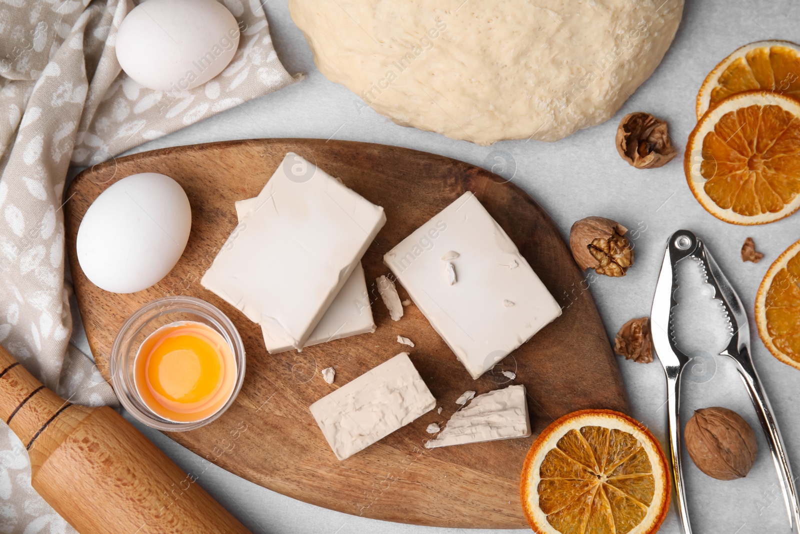 Photo of Yeast and ingredients for dough on light gray table, flat lay