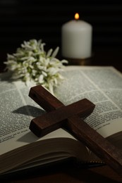Photo of Wooden cross, Bible, flowers and church candle on table