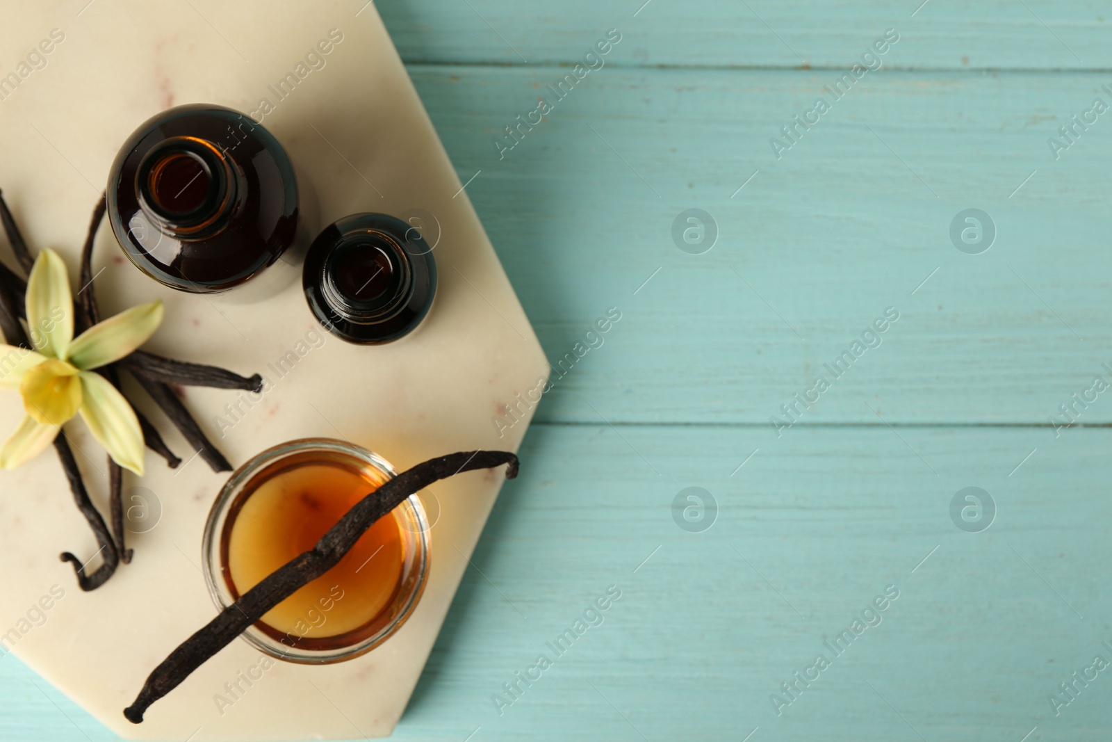 Photo of Flat lay composition with vanilla extract on blue wooden table. Space for text