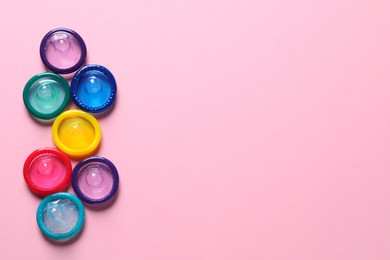 Photo of Colorful condoms on pink background, flat lay. Space for text