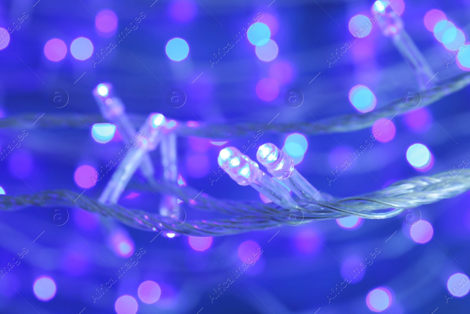 Photo of Beautiful Christmas lights on color background, closeup