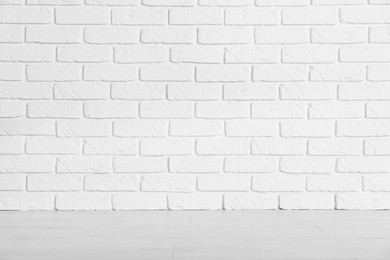 Photo of Beautiful white brick wall and wooden floor in clean empty room