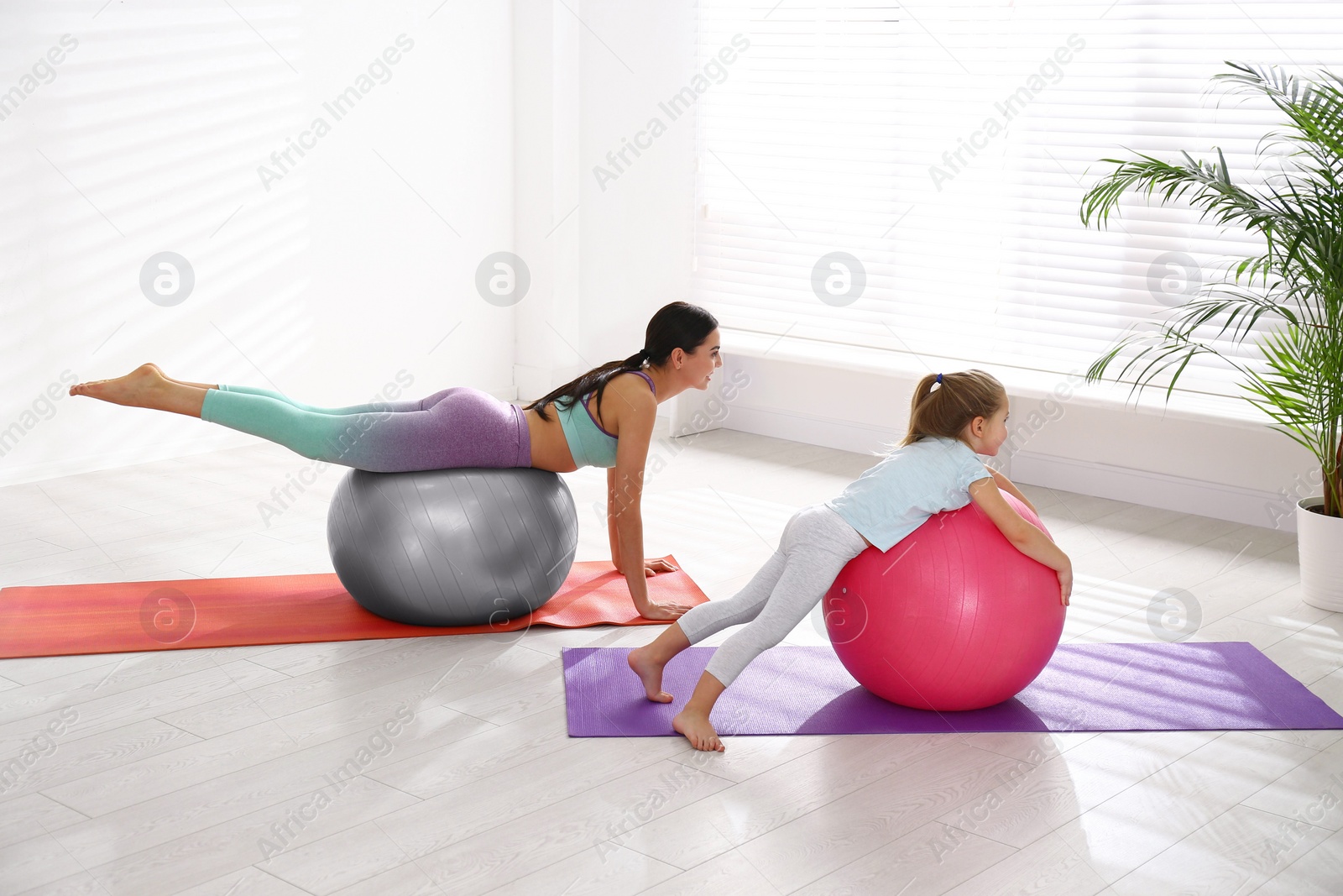 Photo of Woman and daughter doing exercise with fitness balls at home