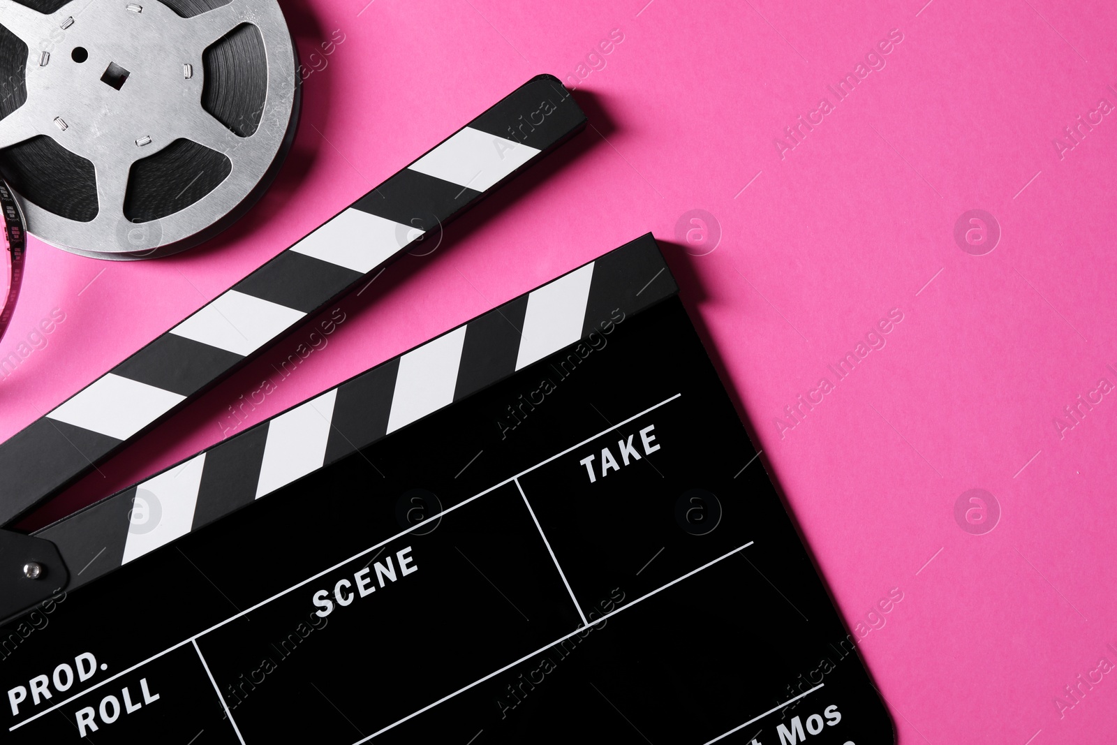 Photo of Clapperboard and film reel on pink background, flat lay. Space for text