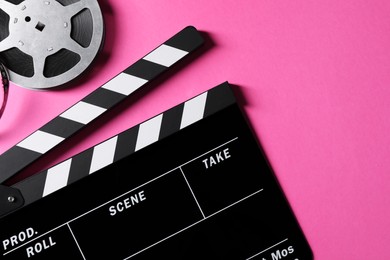 Photo of Clapperboard and film reel on pink background, flat lay. Space for text