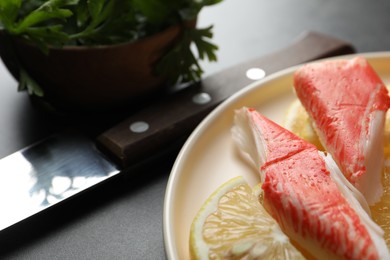 Delicious crab sticks with lemon slices on grey table, closeup