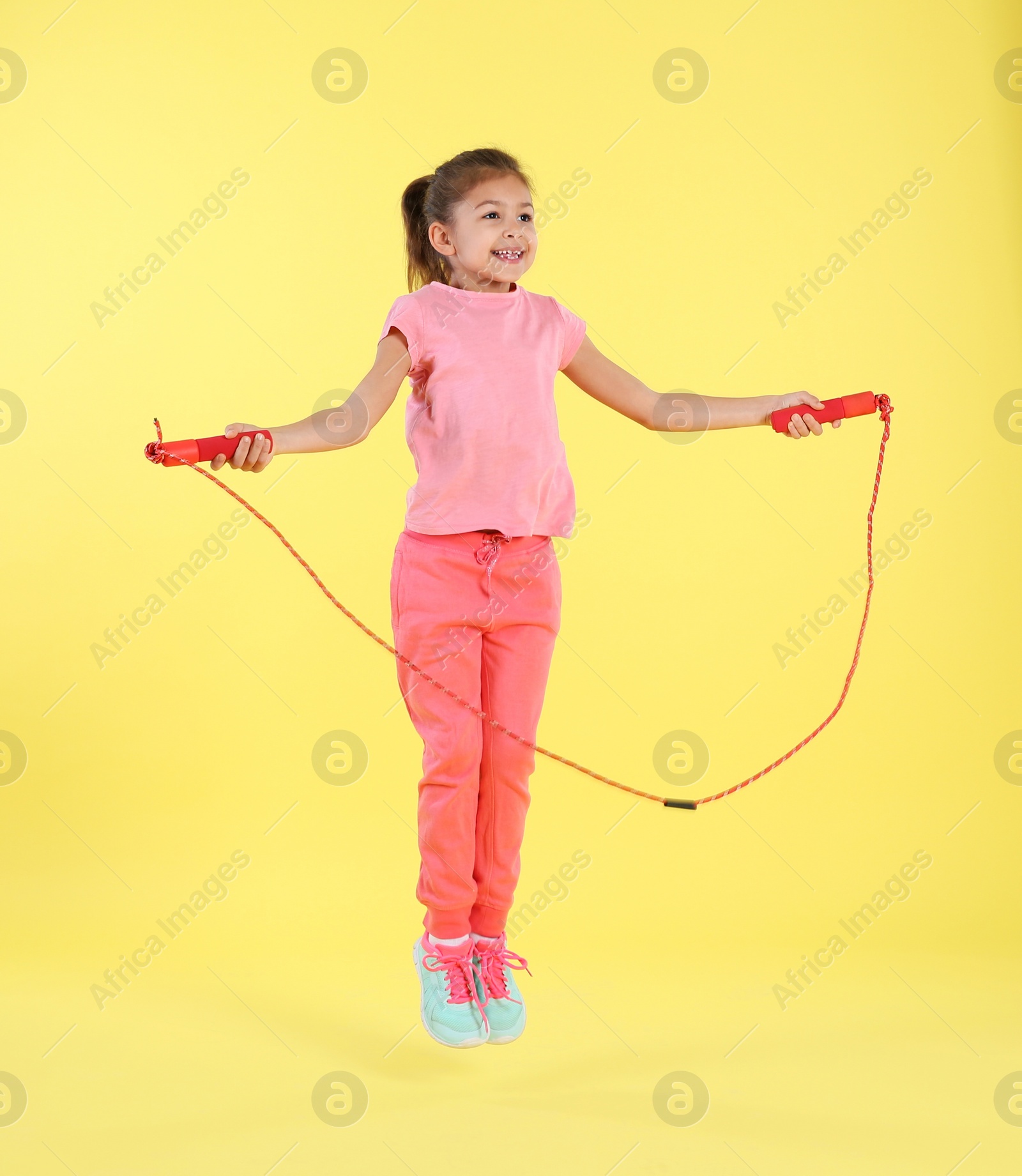 Photo of Full length portrait of girl jumping rope on color background