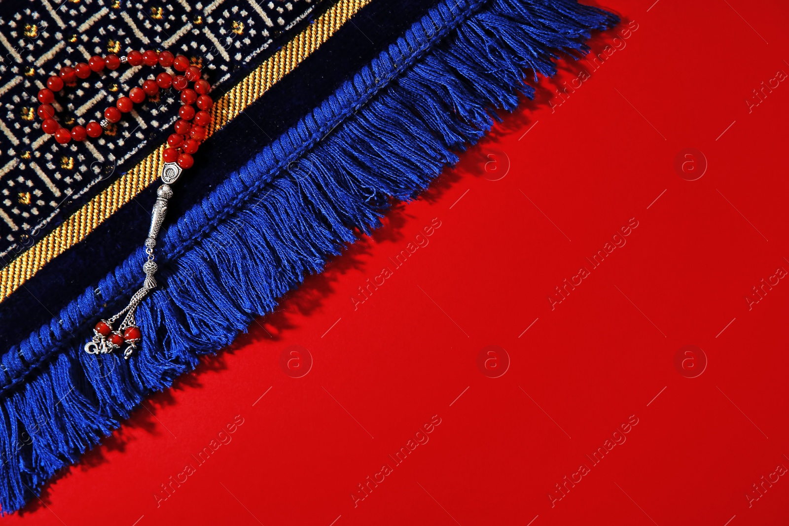 Photo of Muslim prayer beads, rug and space for text on color background, top view