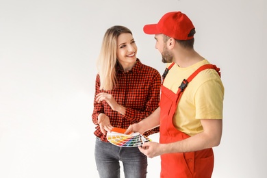 Male decorator and young woman with color palette on white background