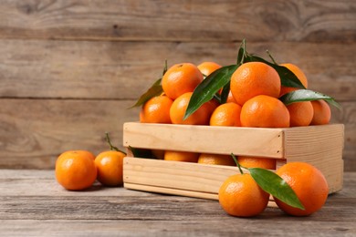 Delicious tangerines with leaves on wooden table. Space for text