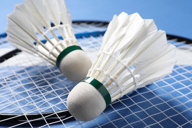 Feather badminton shuttlecocks and rackets on blue background, closeup