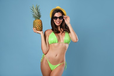 Photo of Beautiful woman in stylish bikini with pineapple on blue background