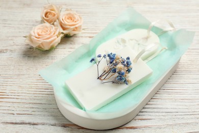 Scented sachets and flowers on white wooden table