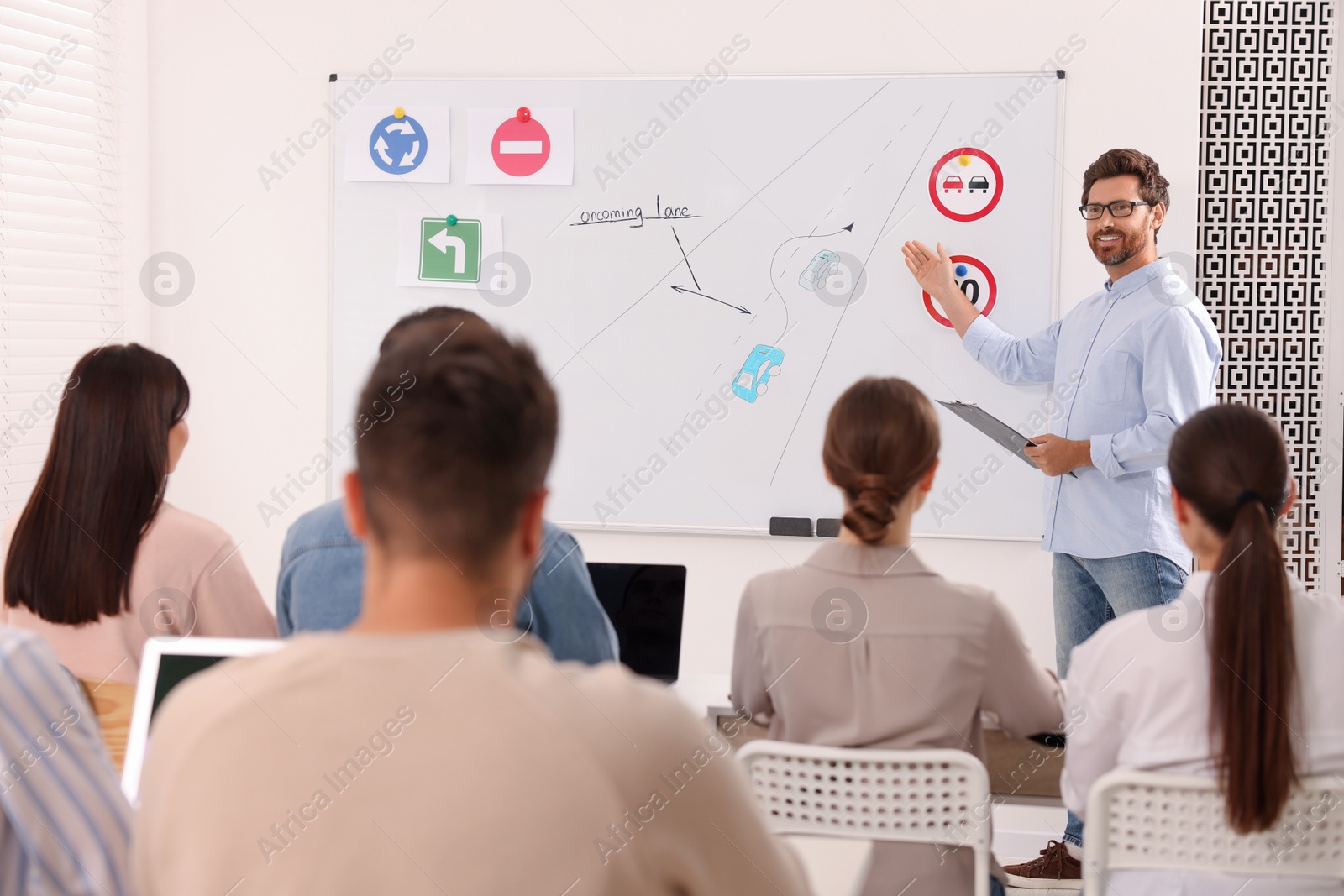 Photo of Teacher explaining traffic rules to audience during lesson in driving school