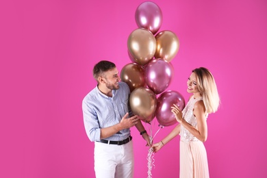 Photo of Young couple with air balloons on color background