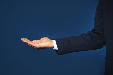 Photo of Businessman holding something on color background, closeup of hand