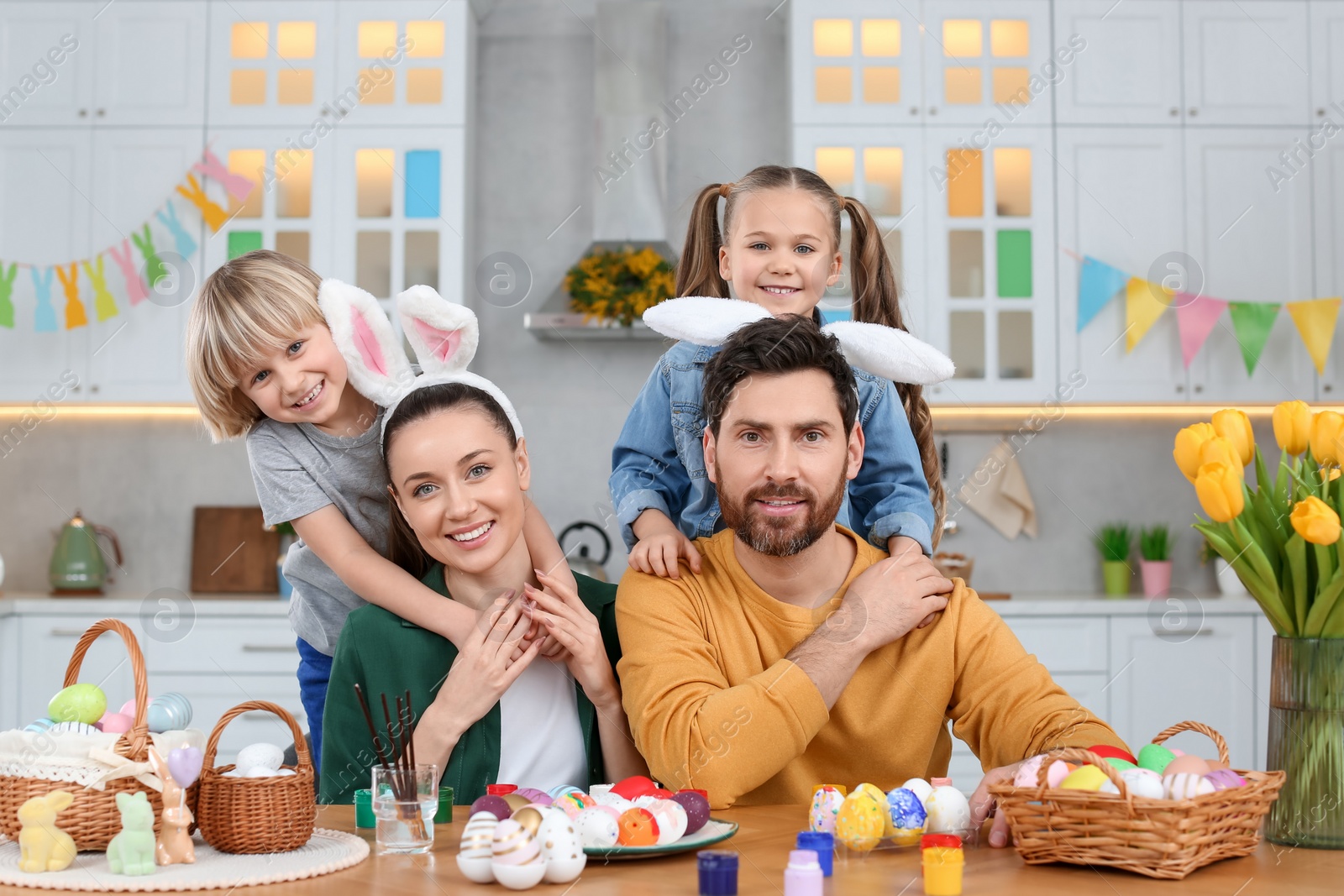 Photo of Portrait of happy family and Easter eggs at table in kitchen