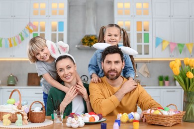 Photo of Portrait of happy family and Easter eggs at table in kitchen