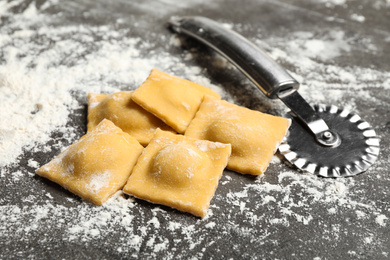 Ravioli and cutter on grey table, closeup. Italian pasta