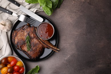 Photo of Tasty grilled meat, rosemary and marinade served on brown textured table, flat lay. Space for text