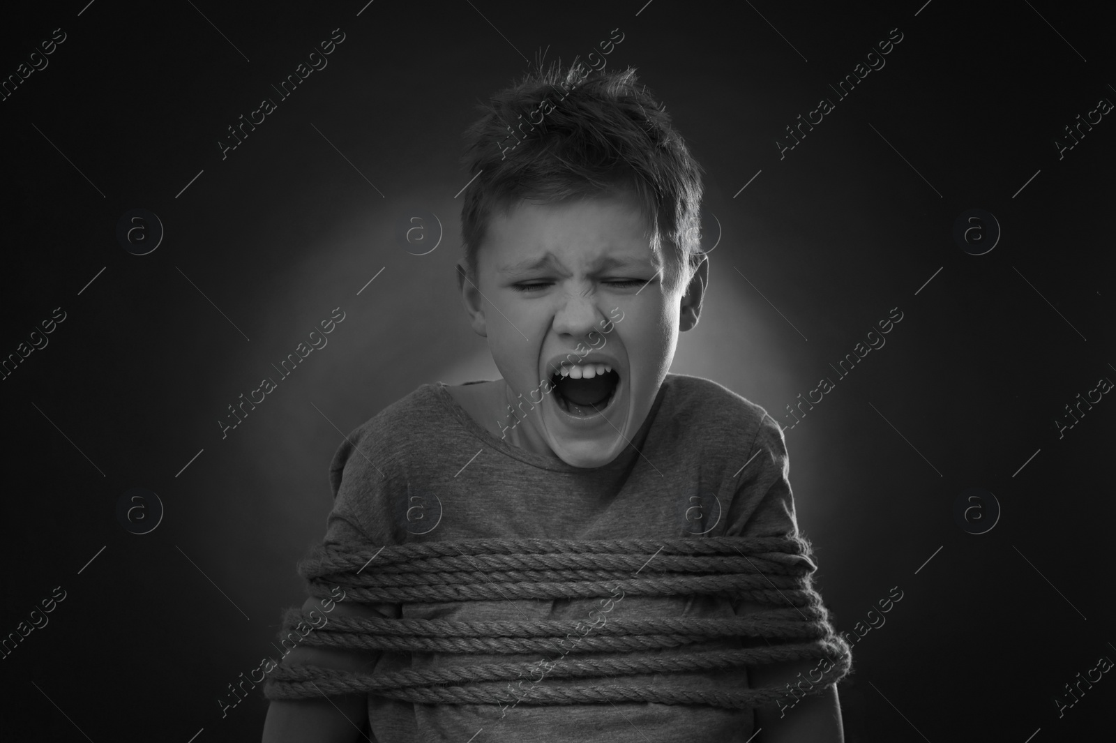 Photo of Scarred little boy tied up and taken hostage on dark background