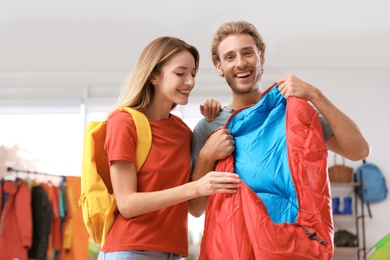 Young couple choosing sleeping bag in store