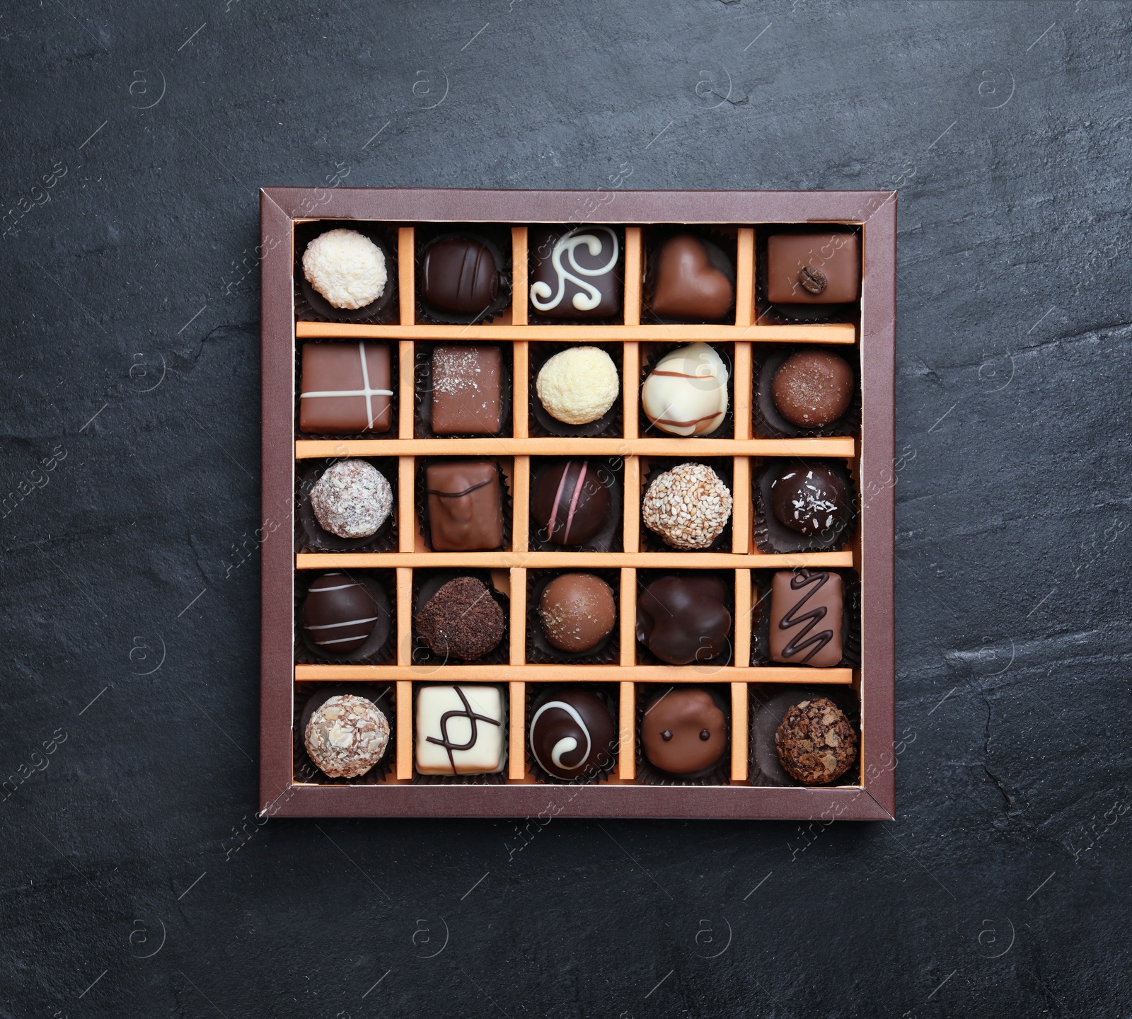 Photo of Box with delicious chocolate candies on black table, top view