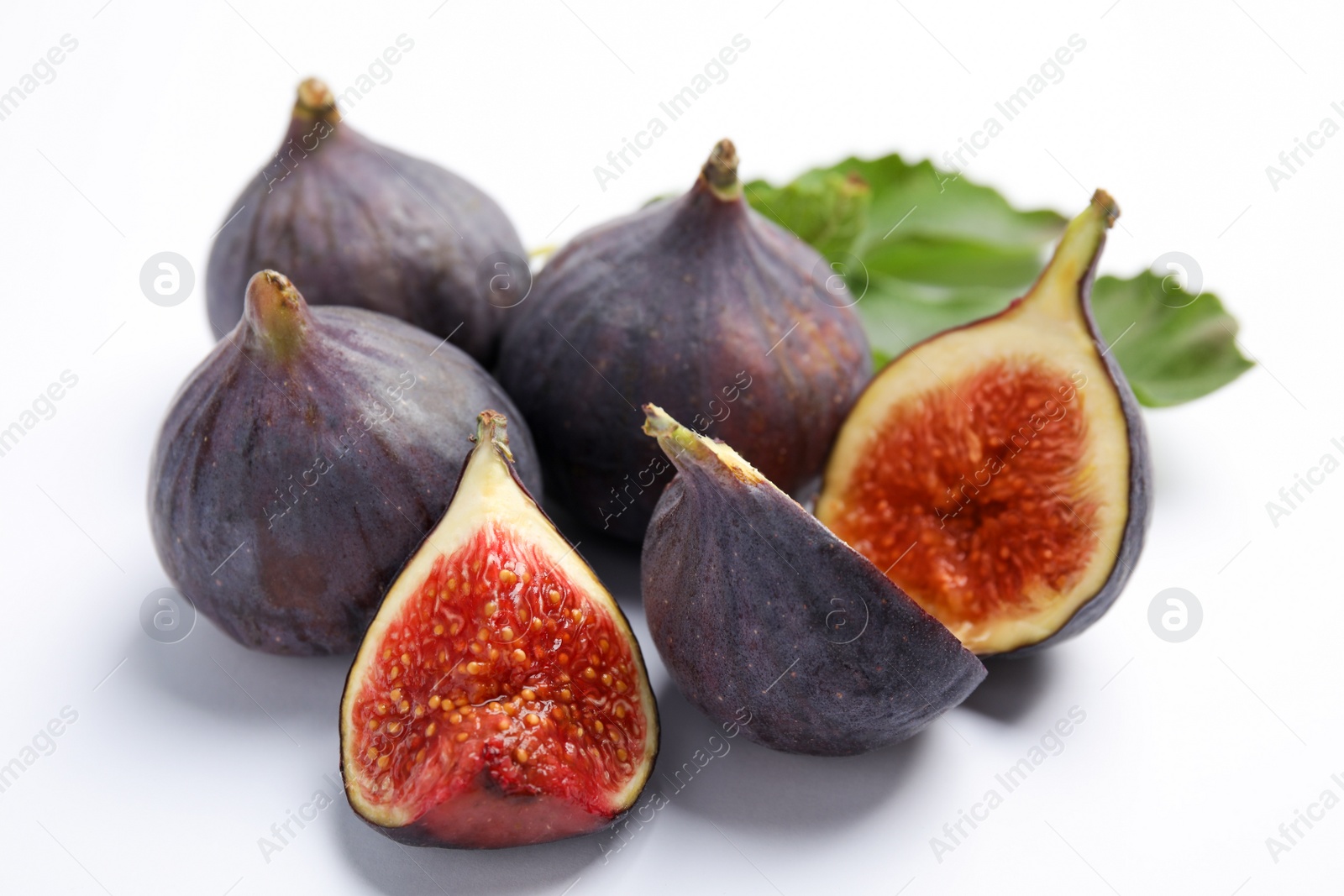 Photo of Delicious ripe figs and green leaf on white background, closeup