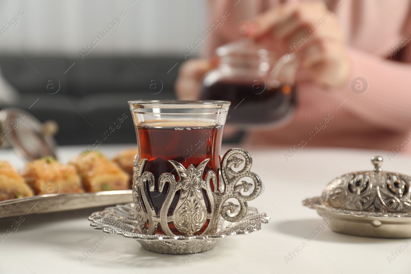 Photo of Woman having delicious Turkish tea at white table, selective focus