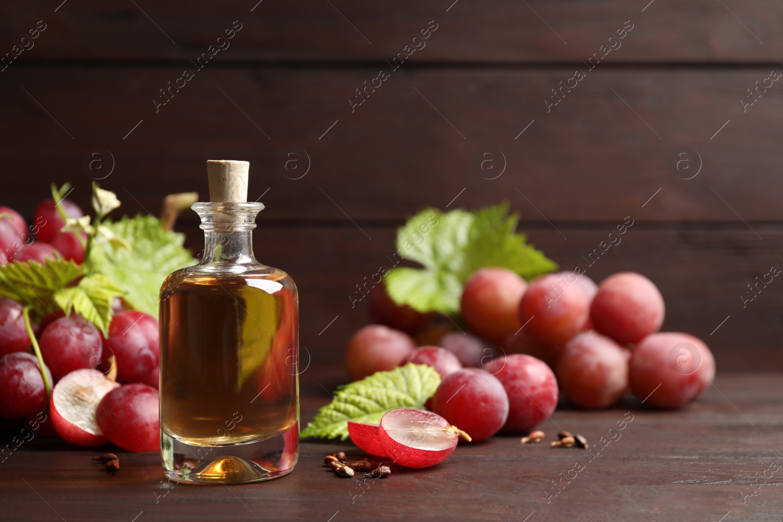 Photo of Bottle of natural grape seed oil on wooden table, space for text. Organic cosmetic