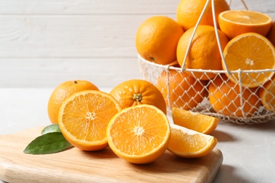 Photo of Wooden board with ripe oranges on table