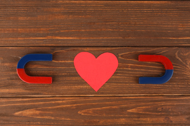 Photo of Magnets and red heart on wooden table, flat lay