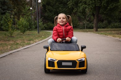 Cute little girl driving children's car outdoors