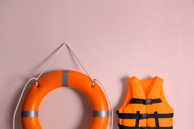 Orange life jacket and lifebuoy on pink background. Rescue equipment