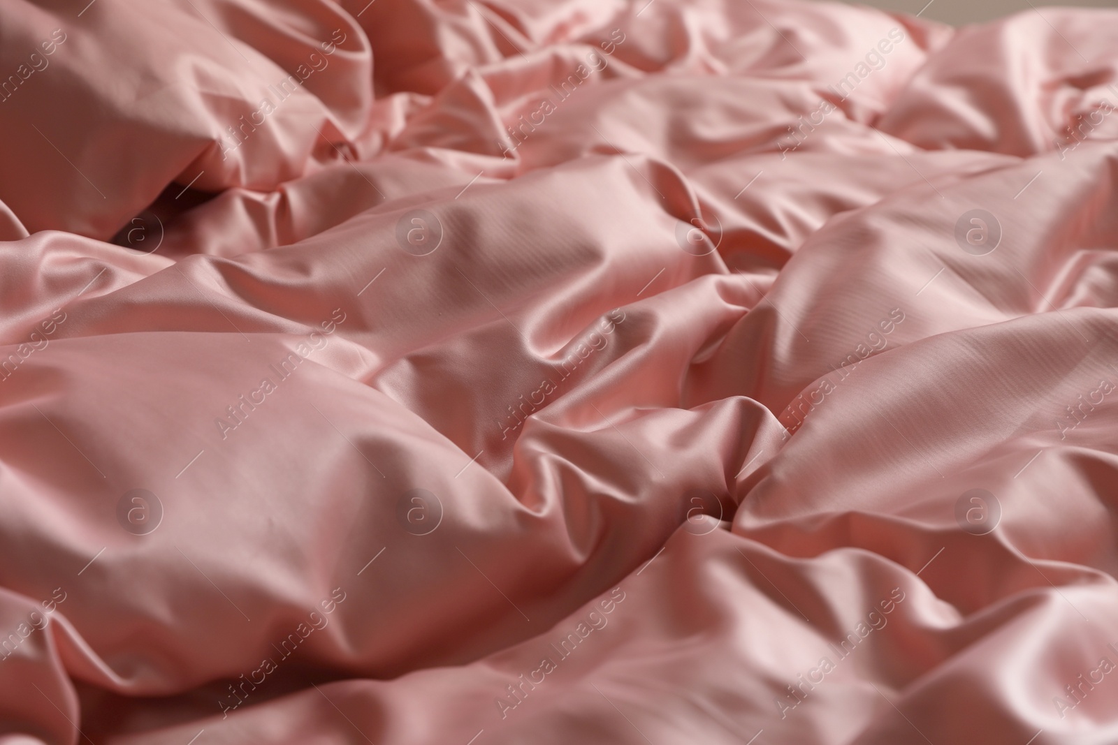 Photo of Closeup view of bed with beautiful pink silk linens