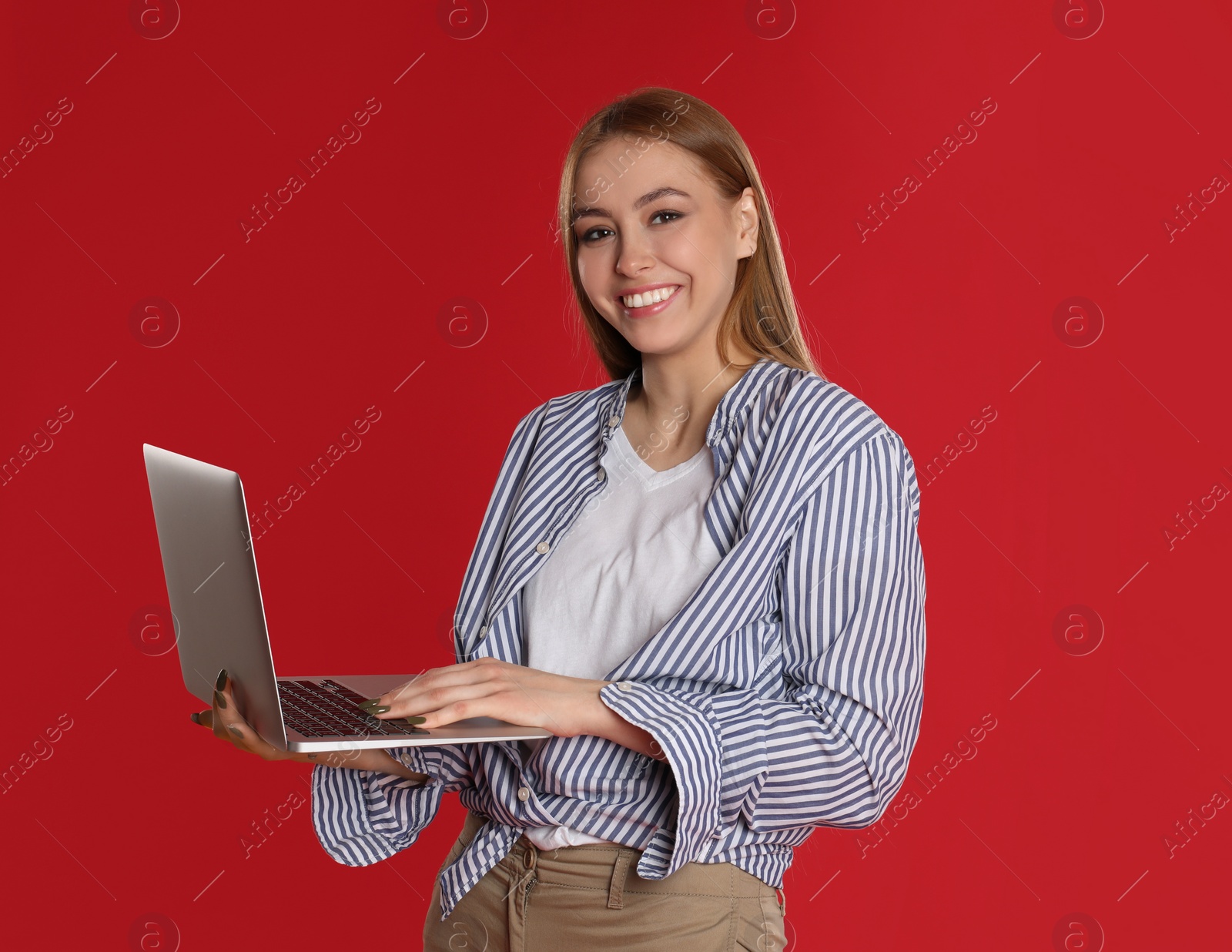 Photo of Teenage girl using laptop on red background