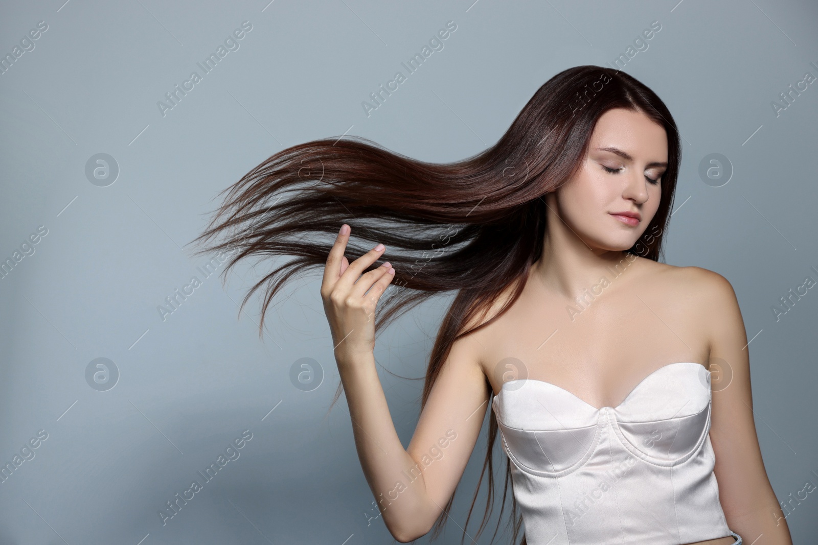 Photo of Portrait of beautiful young woman with healthy strong hair on light gray background