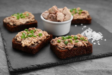 Photo of Tasty sandwiches with cod liver, salt and green onion on light grey table