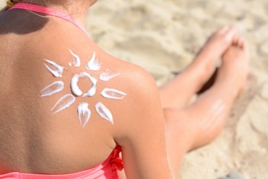 Photo of Little girl with sun protection cream on back outdoors, closeup. Space for text