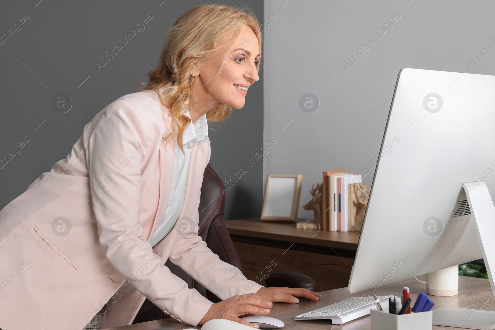 Photo of Happy lady boss working on computer in office. Successful businesswoman