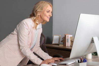 Photo of Happy lady boss working on computer in office. Successful businesswoman