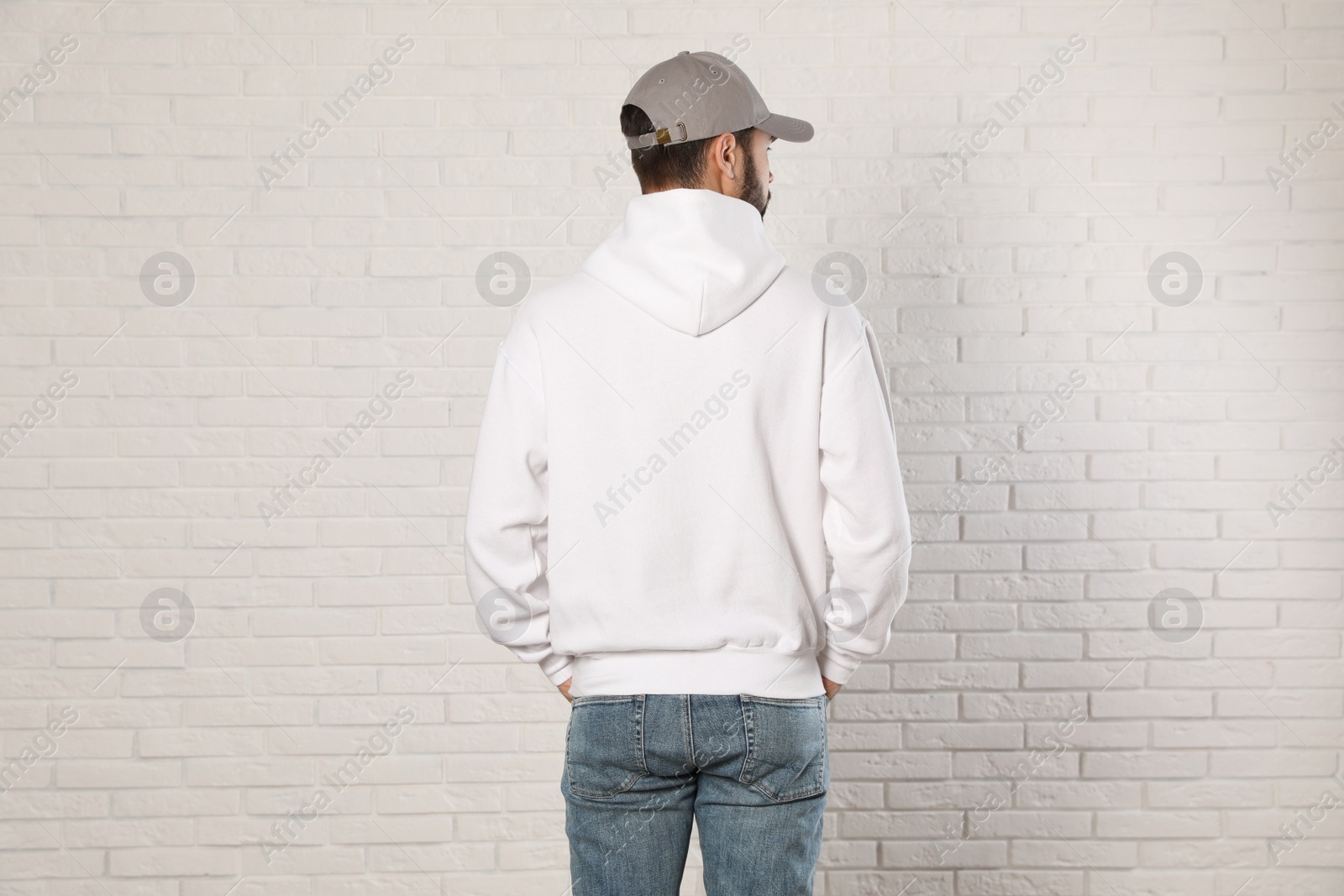 Photo of Young man in sweater at brick wall. Mock up for design