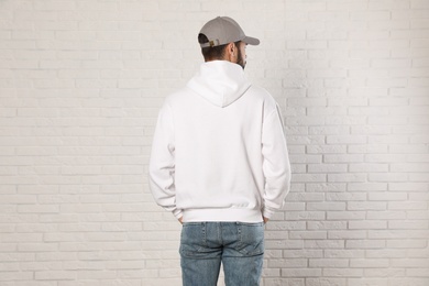 Young man in sweater at brick wall. Mock up for design