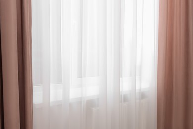 Photo of Elegant window curtains and white tulle indoors. Interior design