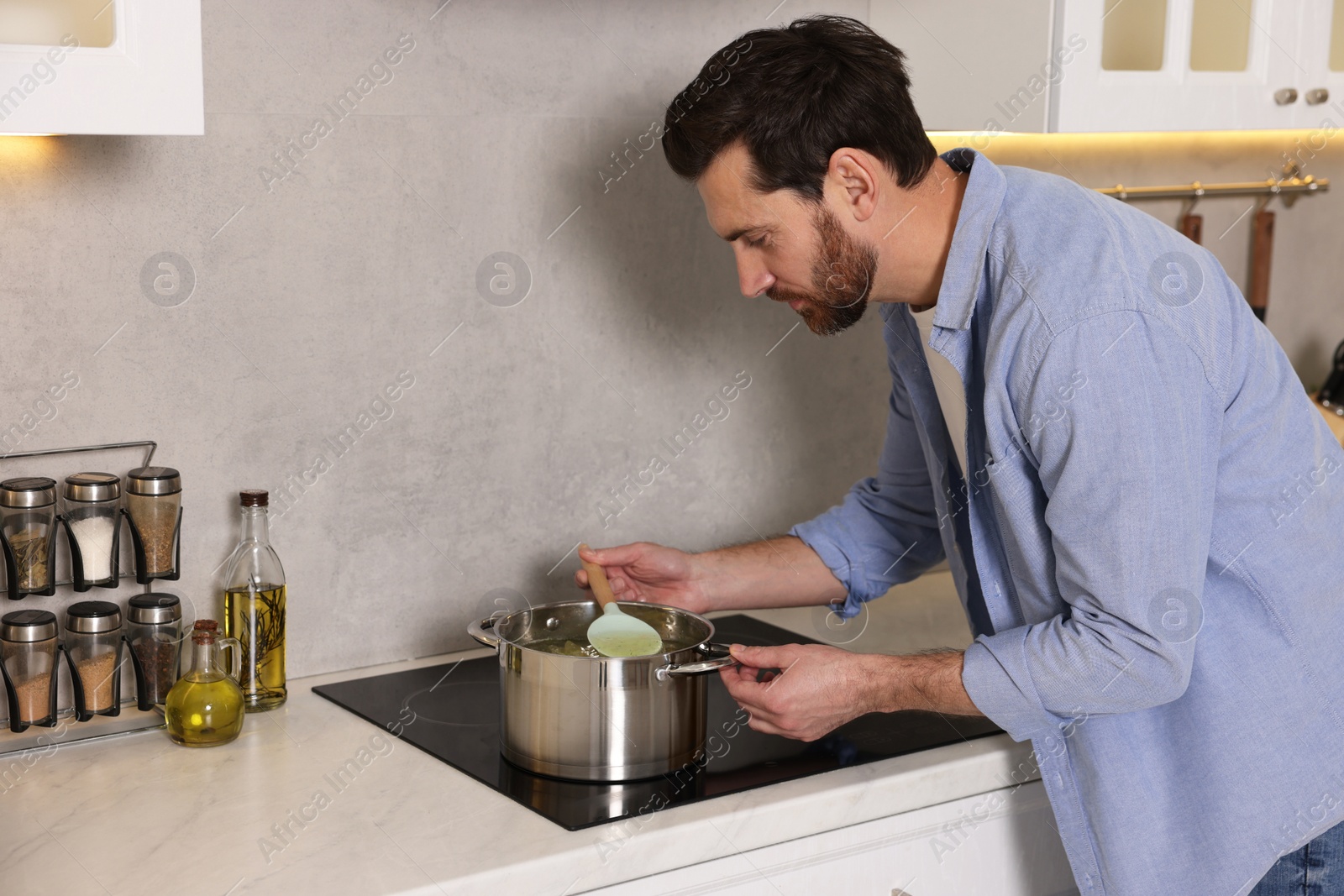 Photo of Man cooking delicious chicken soup in kitchen